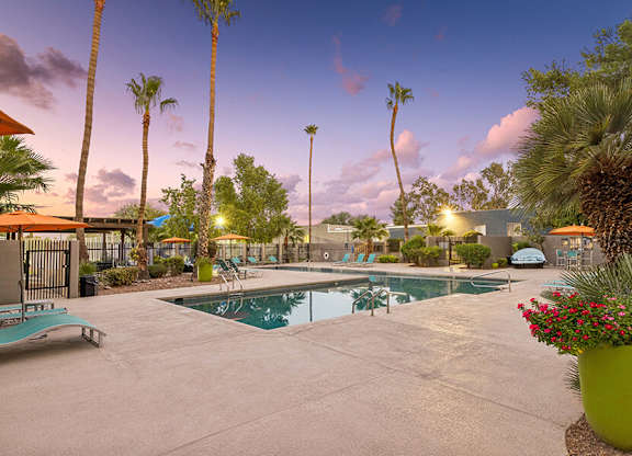 East Tucson, AZ, Pet-Friendly Affordable Apartments - Lakeside Casitas - A Swimming Pool With A Spacious Sundeck, Lounge Chairs, Orange Umbrellas, And Palm Trees.