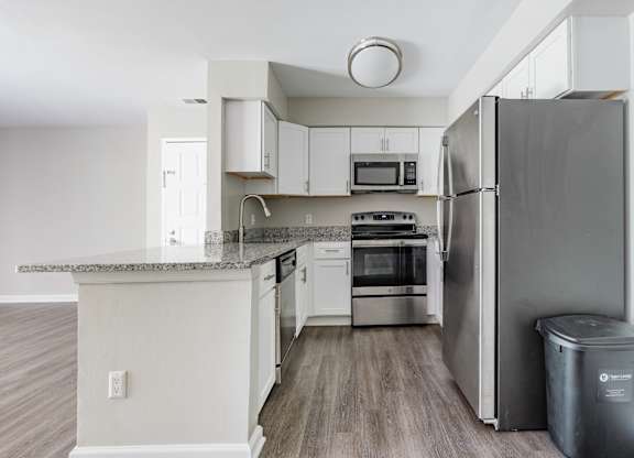 A kitchen with a refrigerator, oven, and microwave.
