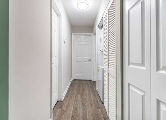 A long, narrow hallway with white doors and a white radiator on the wall.