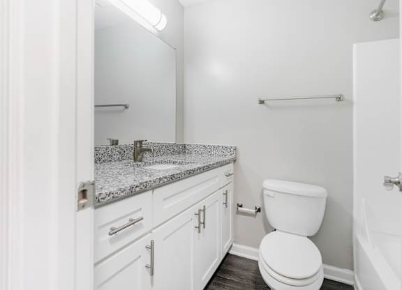 A white bathroom with a toilet, sink, and mirror.