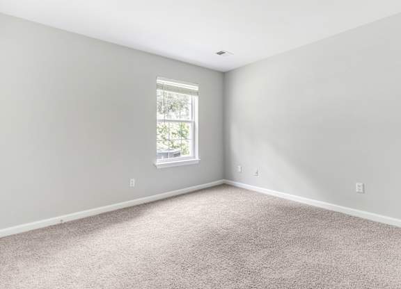 A room with a carpeted floor and a window.