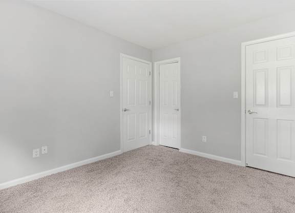 A room with two doors and carpeted floor.