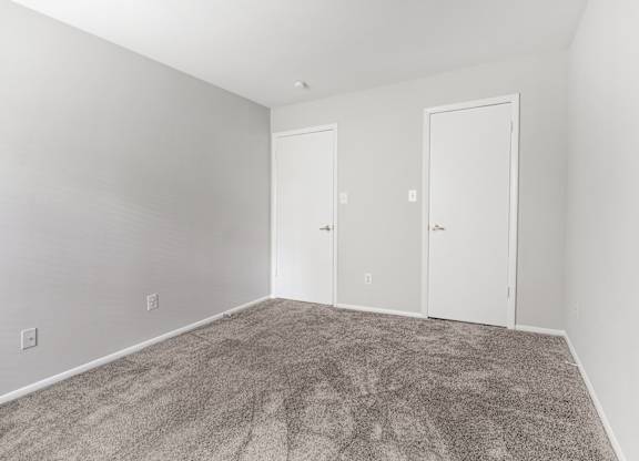 A room with two doors and carpeted floor.