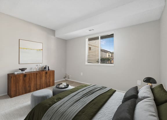 Model Bedroom with Carpet and Window View at Liberty Creek Apartments in Aurora, CO.