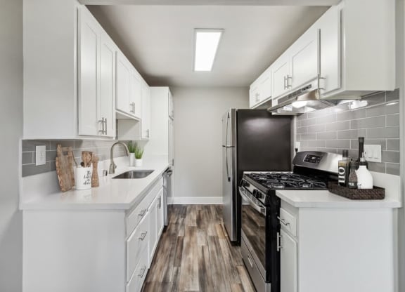 Model Kitchen with Wood-Style Flooring & White Cabinets at Forest Park Apartments in El Cajon, CA.