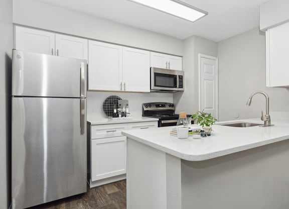 Model Kitchen with White Cabinets and Wood-Style Flooring at Grand Pavilion Apartments in Tampa, FL.