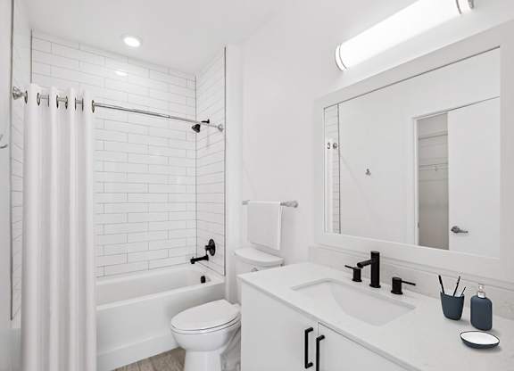 Model Bathroom with White Cabinets, Wood-Style Flooring and Shower/Tub at Stella Apartments located in New Carrollton, MD.