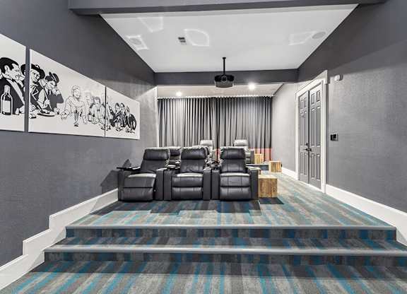 Community Theater Room with Lounge Chairs and Projector Screen at Chapel Hill Apartments located in Lewisville, TX.