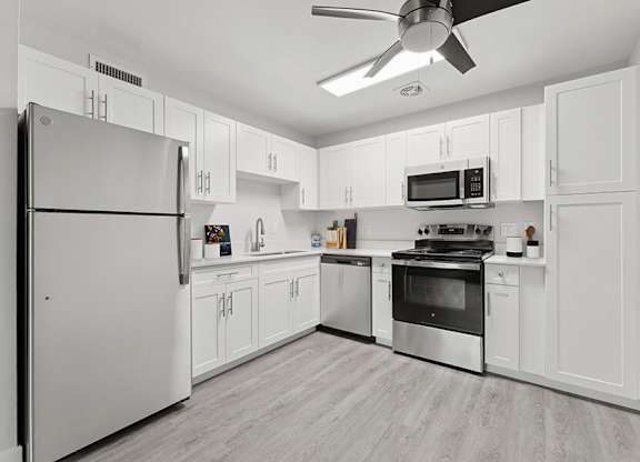 Model Kitchen with White Cabinets and Wood-Style Flooring at The Grove at Walnut Creek Apartments located in Walnut Creek, CA.
