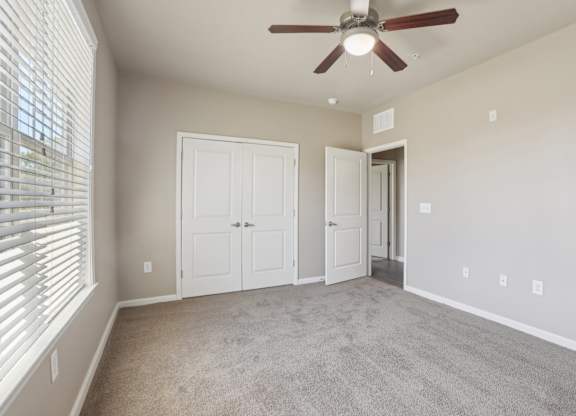 Model bedroom with a ceiling fan and two doors.