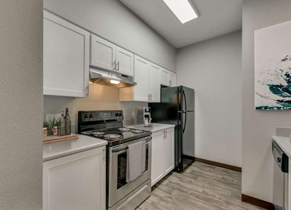 Model Kitchen with White Cabinets and Wood-Style Flooring at Landings at Morrison Apartments located in Gresham, OR.