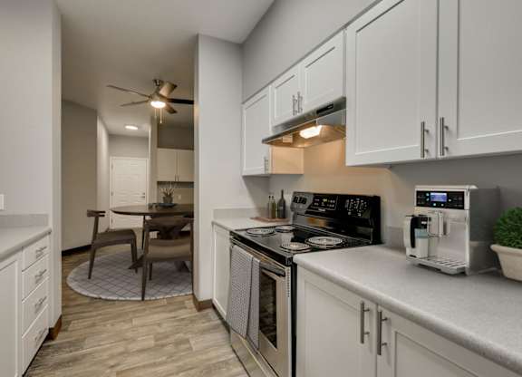 Model Kitchen with White Cabinets and Wood-Style Flooring at Landings at Morrison Apartments located in Gresham, OR.