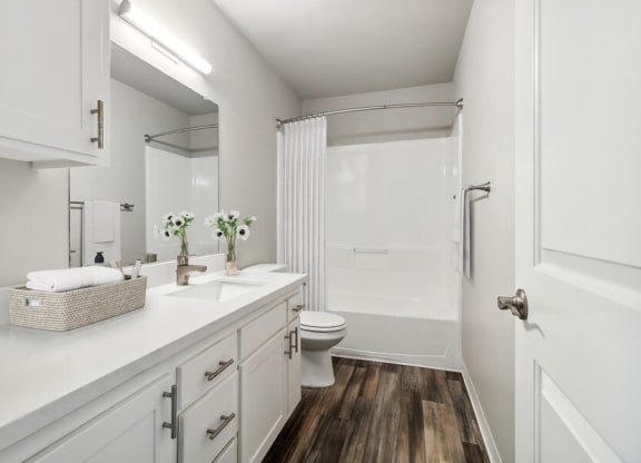 Model Bathroom with Bathtub/Shower, Wood-Style Flooring & White Cabinets at Forest Park Apartments in El Cajon, CA.