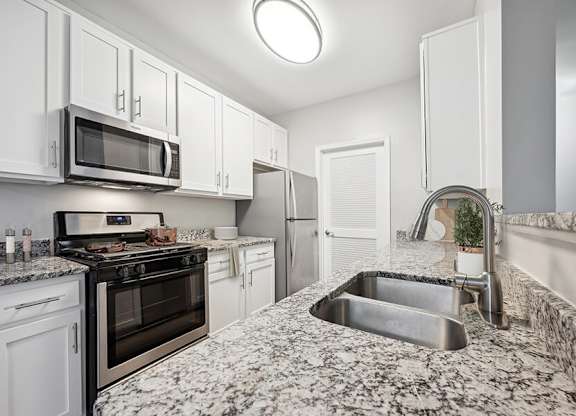 Model Kitchen with White Cabinets and Wood-Style Flooring at Dulles Green Apartments located in Herndon, VA.