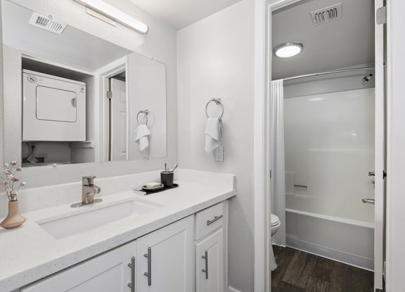 Model Bathroom with White Cabinets, Wood-Style Flooring & Shower/Tub at Crystal Creek Apartments in Phoenix, AZ.