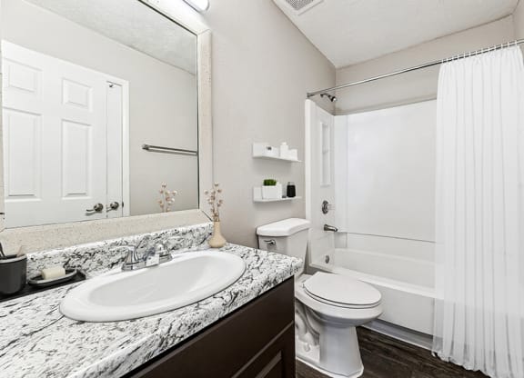 Model Bathroom with Dark Cabinets, Wood-Style Flooring and Shower/Tub at Paramont Apartments in Duluth, GA.