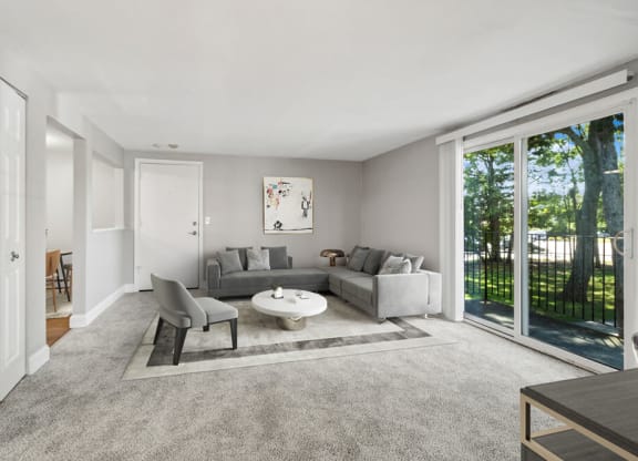 Model living room with a gray couch and a white coffee table in front of a sliding glass door