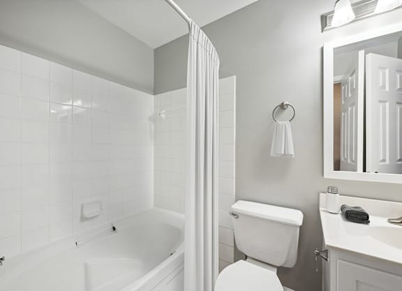 Model Bathroom with White Cabinets, Wood-Style Flooring and Shower/Tub at Dulles Green Apartments located in Herndon, VA.