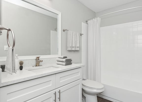 Model Bathroom with White Cabinets, Wood-Style Flooring and Shower/Tub at Grand Pavilion Apartments in Tampa, FL.