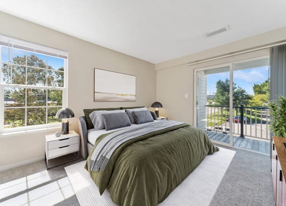 Model Bedroom with Carpet and Patio at The Commons at Haynes Farm Apartments in Boston, MA.