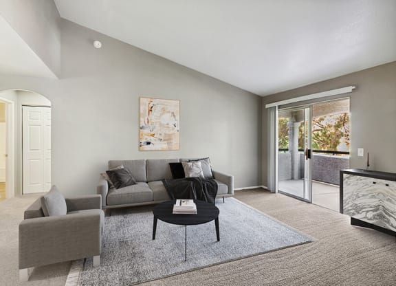 Model Living Room with Carpet and Patio Accessibility at Verraso Apartments in Las Vegas, NV.