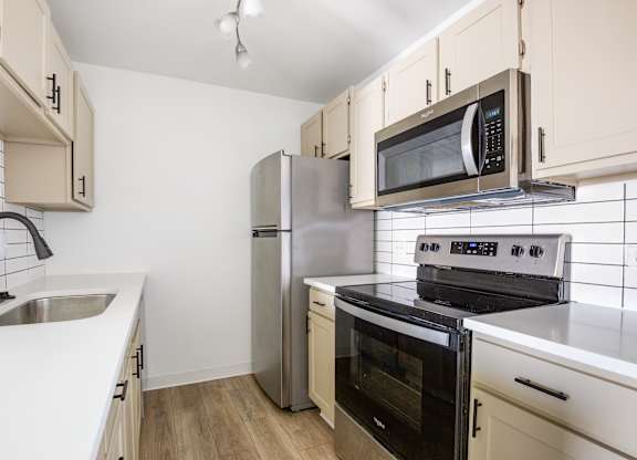 Model kitchen with a stove, oven, refrigerator, and microwave.