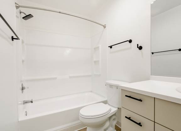 Model bathroom with a toilet, sink, and bathtub.