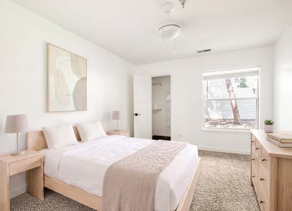Model bedroom with a bed, nightstand, and a painting on the wall.