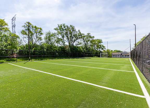 Community soccer field surrounded by a fence and trees.