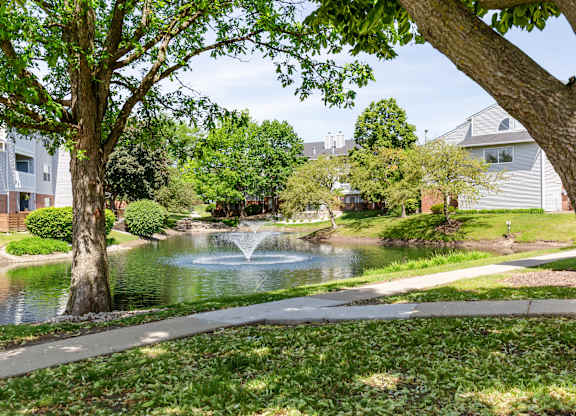 Community park with a walking path, pond and a fountain.