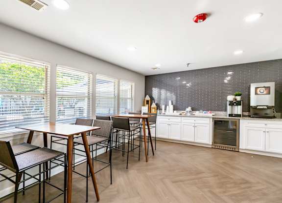 Community club house seating area with a coffee machine, elevated chairs and tables.