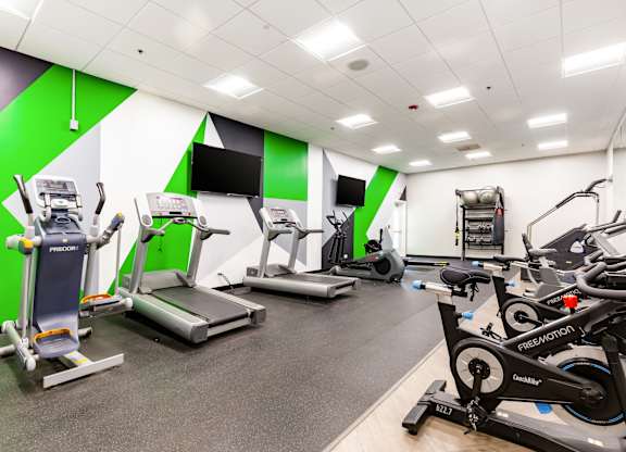 Community gym with a variety of exercise equipment including treadmills, stationary bikes, and weight machines.