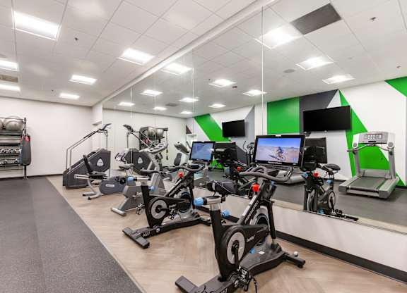 Community gym with a variety of exercise equipment including treadmills, stationary bikes, and weight machines.