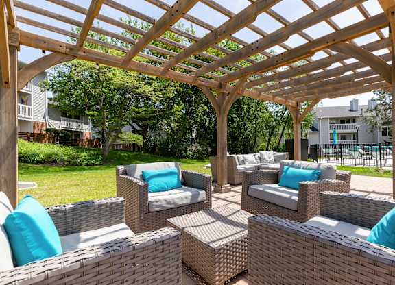 Community wooden pergola over a patio with wicker furniture.