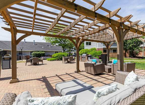 Community wooden pergola shades a patio with wicker furniture.