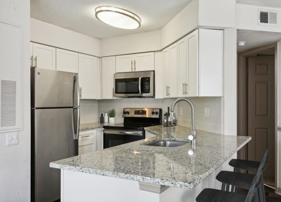 Model kitchen with white cabinets and a granite counter top at Retreat at Crosstown Apartments