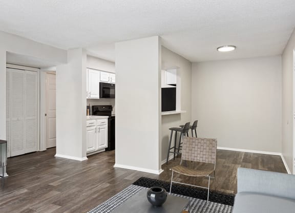 Model Living Room with Wood-Style Flooring and View of Kitchen at Grand Pavilion Apartments in Tampa, FL.