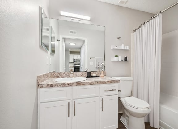 Model Bathroom with White Cabinets, Wood-Style Flooring and Shower/Tub at Westland Park Apartments in Jacksonville, FL.