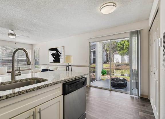 Model kitchen and living room with a sliding glass door leading to a patio at Retreat at Crosstown Apartments
