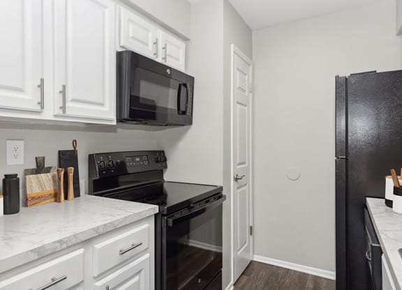 Model Kitchen with White Cabinets and Wood-Style Flooring at Grand Pavilion Apartments in Tampa, FL.