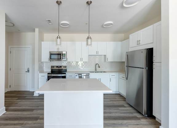 A modern kitchen with a white island and stainless steel appliances.