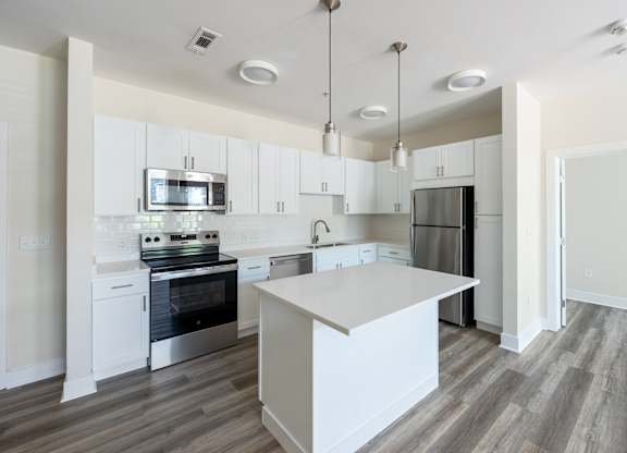 A modern kitchen with a white island and stainless steel appliances.