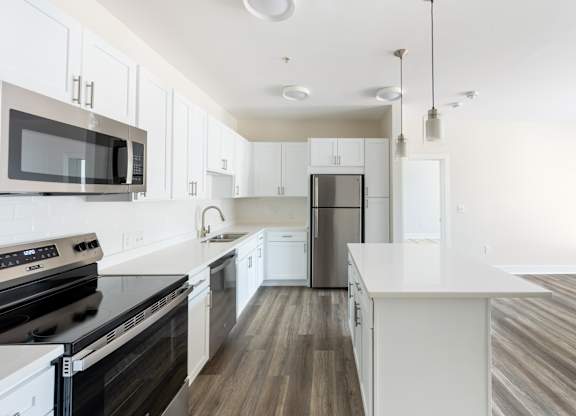 A modern kitchen with white cabinets and a black stove top oven.
