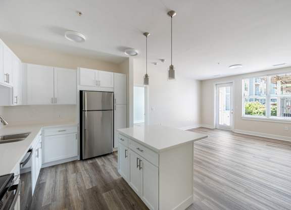 A kitchen with white cabinets and a stainless steel refrigerator.