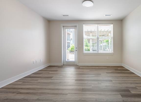 A room with a wooden floor and a sliding glass door leading outside.
