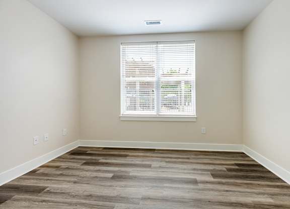 A room with a window and wooden flooring.