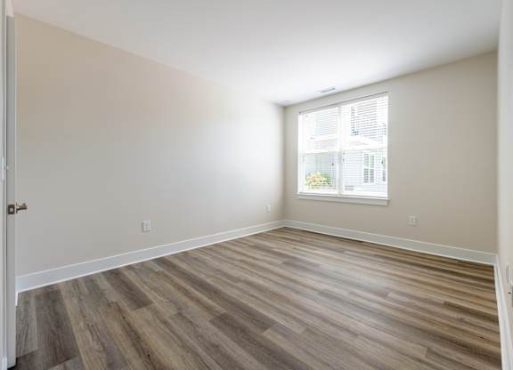 A room with wooden flooring and a window.