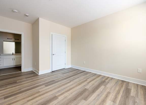 A room with a white door and wooden flooring.