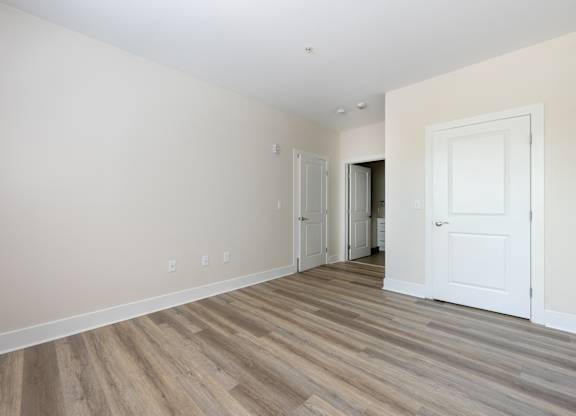 A room with a white door and a wooden floor.
