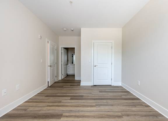 A long, empty hallway with a white door at the end.
